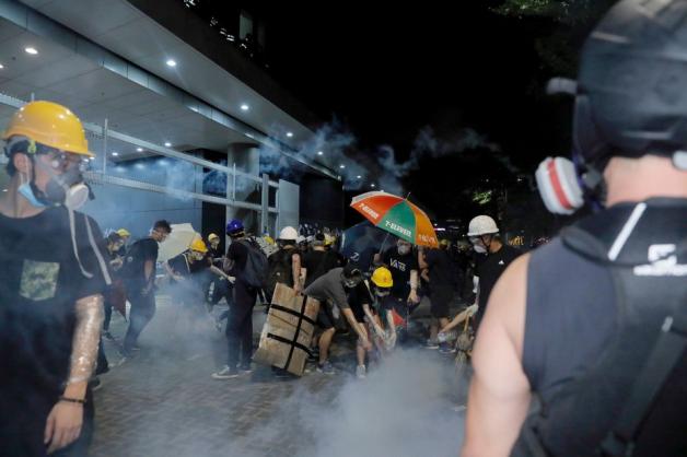 Demonstranten schütten vor dem Parlament Wasser auf Kanister, die mit Tränengas gefüllt sind. Foto: dpa/Kin Cheung/AP