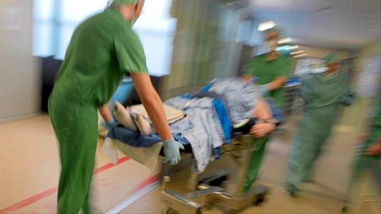 Ein Mediziner-Team fährt in einer Klinik nach einer Operation einen Patienten im Bett durch den Klinikflur. 