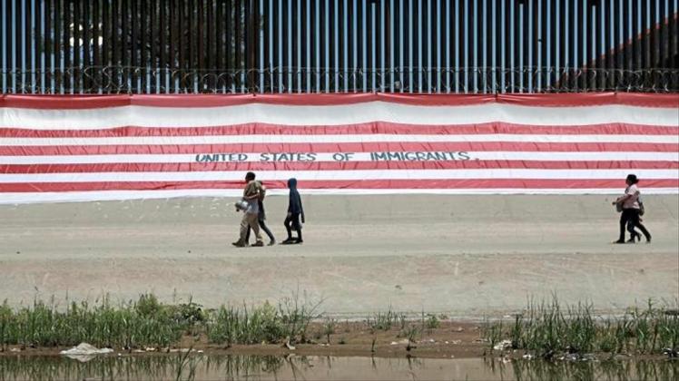 Migranten gehen in Ciudad Juarez in Mexiko an einem Grenzzaun vorüber. 
