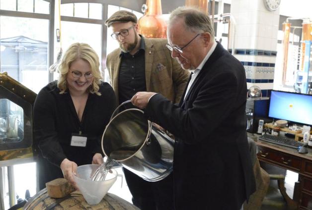 Unter Aufsicht der Harzer Whiskymacher Martina Röhrer und Alexander Buchholz befüllt Stephan Weil ein Whiskyfass. Foto: Klaus Wieschemeyer