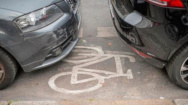 Geparkte Autos stehen auf einem Radweg. 