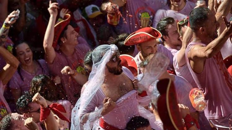 Weiß-Rot gekleidete Menschen feiern zu Beginn des „Sanfermines“-Festes, während sie auf das Abfeuern der Eröffnungsrakete „Chupinazo“ warten. 