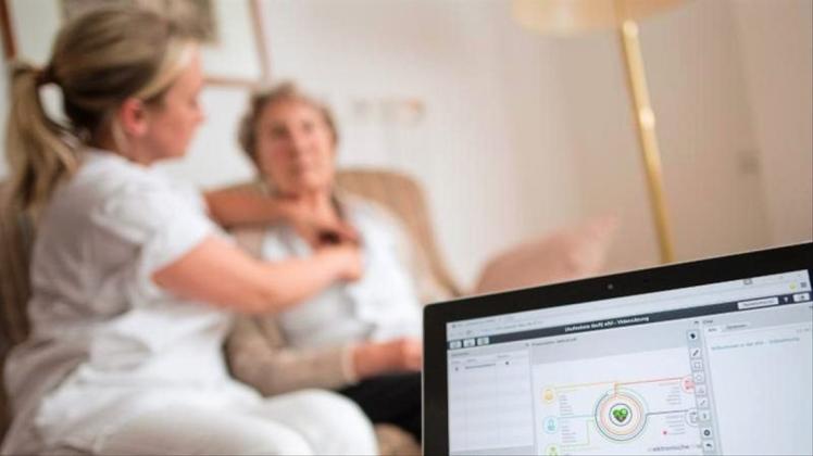 Eine Pflegerin legt einer Bewohnerin im Rahmen einer elektronischen Visite ein EKG-Gerät an, dass die Daten an einen Tablet-Computer und von dort aus zum Arzt überträgt.