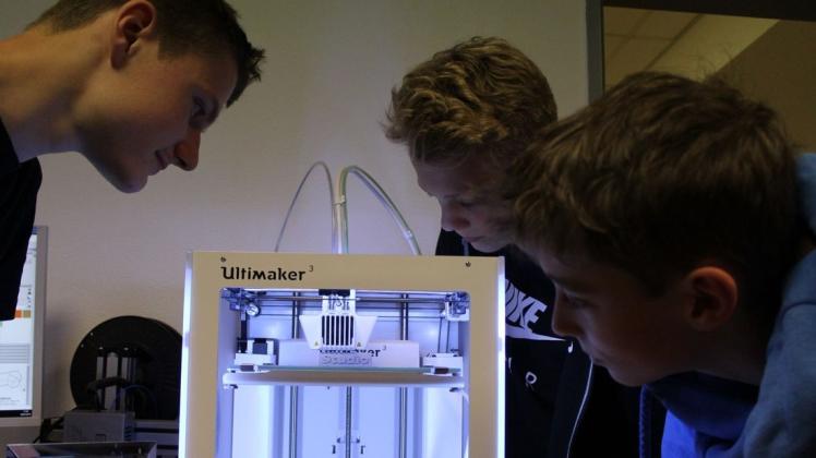 Was druckt denn da? Kieran Smith, Tom Adomeit und Leander Schöne (von links) beobachten den 3D-Drucker bei der Arbeit, in diesem Fall, wie er ein Schild für das Druckstudio erstellt. Foto: Ullrich Schellhaas