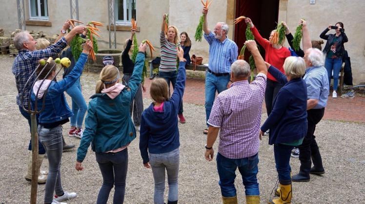 Die „Rulle-vorwärts-Schauspielgruppe“, hier in der Rolle der solidarischen Öko-Bauernhof-Gemeinde, übt den Möhren-Tanz vorm Ruller Haus. Foto: Carolin Hlawatsch