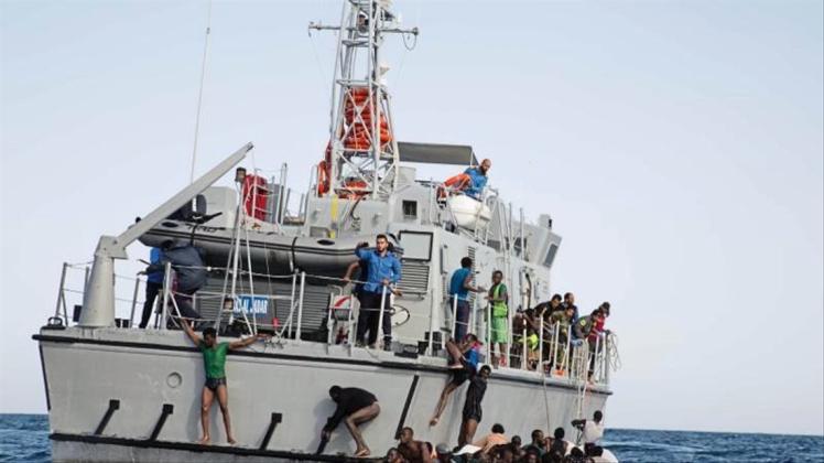 Libysche Flüchtlinge versuchen, an Bord eines Schiffs der libyschen Küstenwache zu gelangen. 
