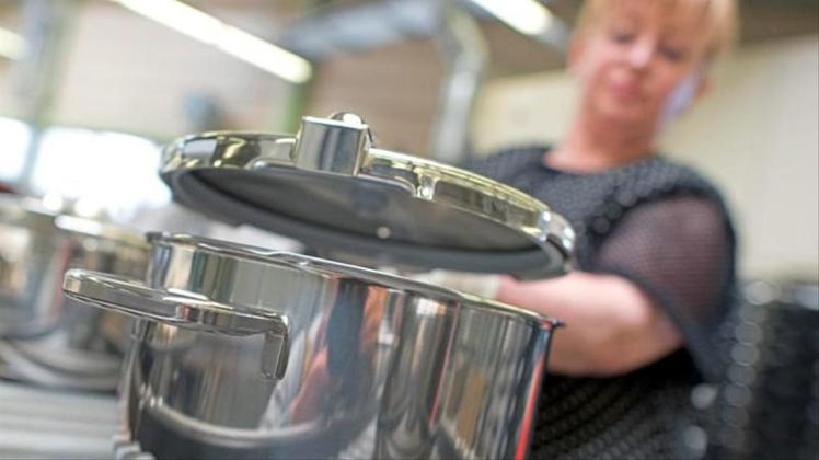 Eine Mitarbeiterin setzt im Stammwerk des Küchengeräteherstellers Württembergische Metallwarenfabrik AG (WMF) in Geislingen einen Deckel auf einen fertiggestellten Topf. 