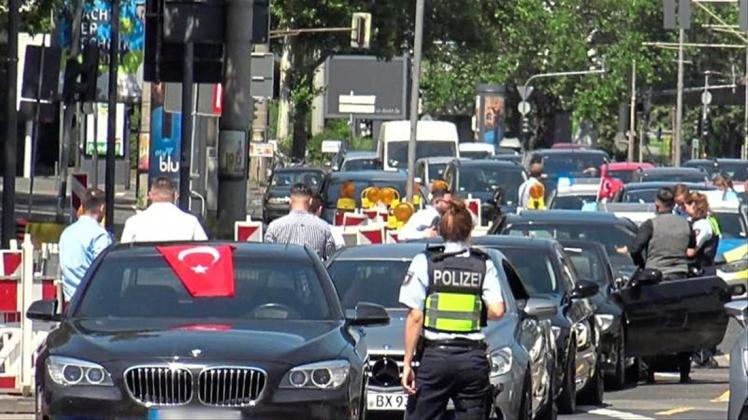 Eine Polizistin steht vor den Fahrzeugen eines türkischen Hochzeutskorsos. 