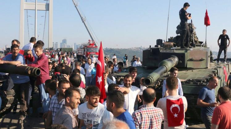 Polizisten und Anhänger von Präsident Erdogan stehen nach dem gescheiterten Putschversuch neben einem Panzer auf der Brücke über den Bosperus. Foto: dpa/Str/EPA