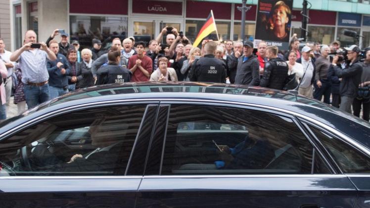 Bundeskanzlerin Angela Merkel (CDU) verlässt in ihrem Dienstwagen vor Demonstranten das Albertinum. Foto: dpa/Sebastian Kahnert