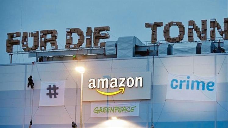 Greenpeace-Aktivisten hängen am Gebäude der Amazon-Logistik Winsen Transparente auf. 