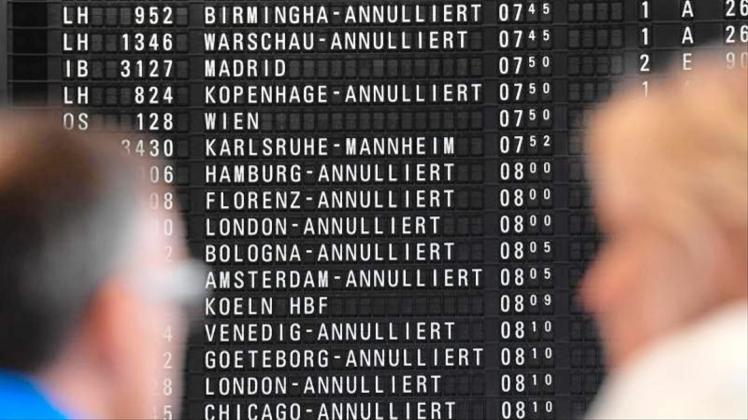 Fluggäste stehen im Terminal 1 des Frankfurter Flughafens vor einer Anzeigetafel, auf der annullierte Flüge angezeigt sind. 