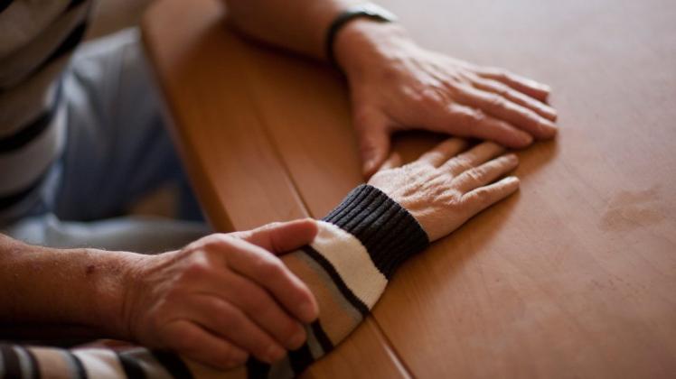Ein Mann hält die Hand seiner Ehefrau, die an Alzheimer erkrankt ist. Foto: dpa