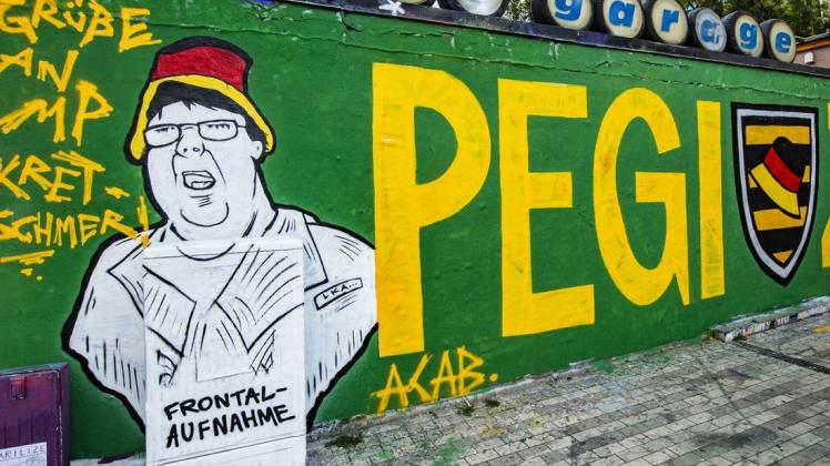 Ein Graffiti mit der Aufschrift "Pegizei" ist an einer Hauswand in der Dresdner Neustadt zu sehen. Thematisiert ist der umstrittene Polizeieinsatz gegen ein ZDF-Team am Rande einer Pegida-Demonstration gegen den Besuch von Kanzlerin Merkel. Foto: dpa/Robert Michael