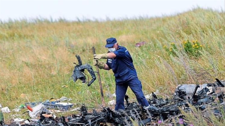 Ein ukrainischer Arbeiter untersucht im Juli 2014 an der Absturzstelle von MH17 Wrackteile der Maschine. 