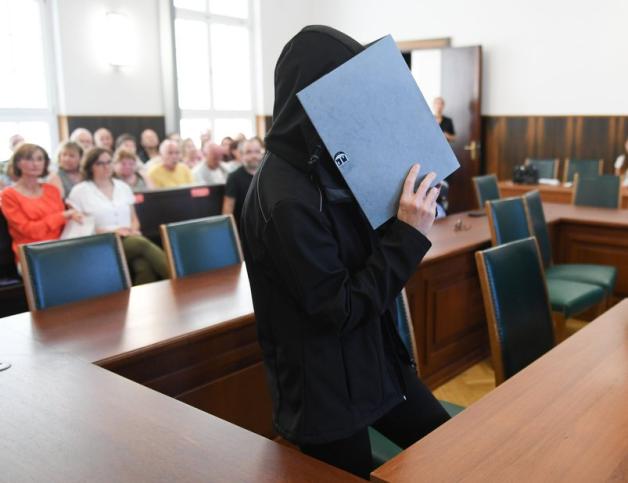 Die Frau nimmt zur Urteilsverkündung im Gerichtssaal des Landgerichts mit einem Aktenordner vor dem Gesicht Platz. Foto: dpa