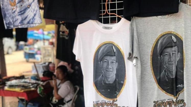 Vor der Tham-Luang-Höhle im äußersten Norden Thailands werden T-Shirts verkauft, auch mit dem Porträt des Ex-Marinetauchers Saman Kunan. 