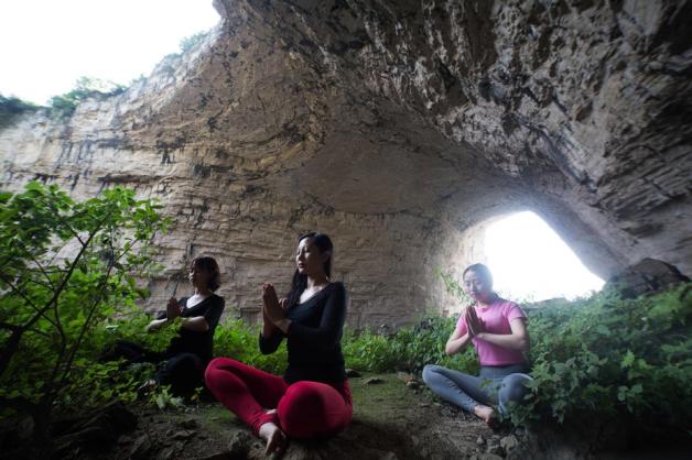 In Chinas Guizhou Provinz machten Frauen Yoga vor einer Höhle. Foto: STR / AFP / China