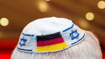 Ein Mann trägt eine Kippa mit eingearbeiteten israelischen und deutschen Fahnen. 