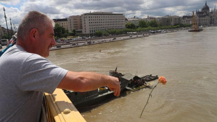 Trauernde werfen Blumen in die Donau in Budapest. Mehr als 20 Menschen werden noch vermisst. Foto: AFP/FERENC ISZA