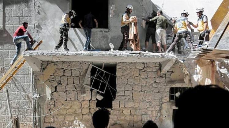 Menschen stehen vor einem Gebäude, das bei einem Luftangriff am 27. Mai durch die syrischen Regierungskräfte beschädigt wurde. 