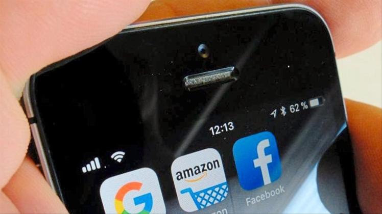 Logos der US-Internetkonzerne Google, Amazon und Facebook sind auf dem Display eines iPhones zu sehen. 