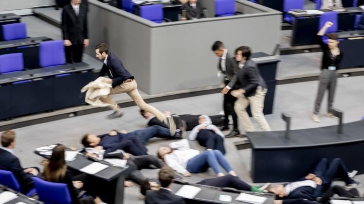 Ein junger Mann rennt bei einer Protestaktion für Klimagerechtigkeit von Fridays For Future im Plenarsaal des Bundestages mit dem Protest-Banner davon, um die Aktion zu stören. Foto: Christoph Soeder/dpa
