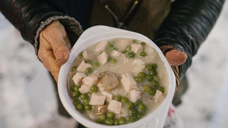 Eine obdachlose Frau hält eine warme Mahlzeit in den Händen. Symbolfoto: Ole Spata/dpa
