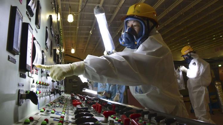 Arbeiter in Schutzanzügen im Hauptkontrollraum im Kernkraftwerk Fukushima Daiichi, wo es 2011 zum Super-Gau kam. Foto: dpa/kyodo