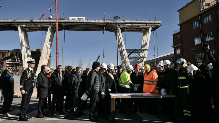 Italiens Regierungschef Giuseppe Conte (mit rotem Helm) lauscht den Experten für den geplanten Brückenabriss. Foto: AFP/Marco BERTORELLO