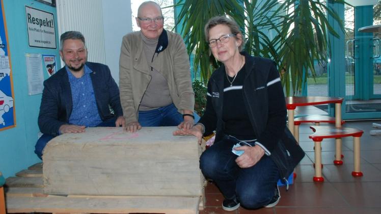Ute Reeh (M.) und Heike Ellner - hier mit Bauamtsleiter Christian Gadow präsentieren im Foyer der Gemeindeverwaltung Karstädt einen Wellerlehmblock.