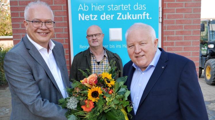 Wilfried Stindt, Projektleiter der Deutsche Glasfaser (rechts), überreichte Bürgermeister Ansgar Brockmann (links) zur Fertigstellung des Glasfasernetzes einen Blumenstrauß. Mit dabei Bauleiter Thomas Engbers.