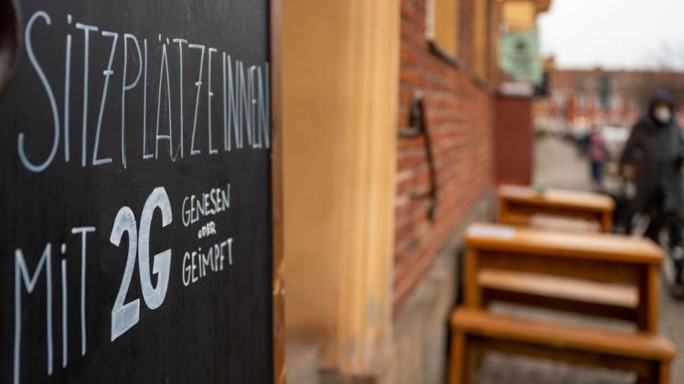 Vor einem Café hängt ein Schild mit Informationen über die 2G-Regel im Innenbereich.