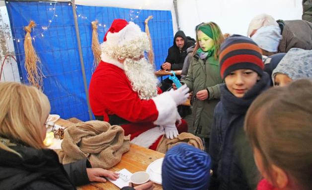 Weihnachtsmann (Sebastian Fischer) hört sich Gedichte und Lieder an und verteilt anschließend kleine Geschenke an die Kinder.