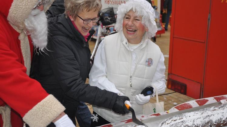 Ein fleißiges Team: Weihnachtsmann Lothar Krips, Stadtpräsidentin Ilka Rohr (M.) und Frau Holle alias Lotti Jenßen hatten wegen der Kälte etwas Mühe beim Anschneiden des Stollens.