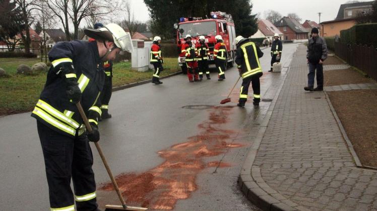 Kameraden der FFw Mestlin binden eine Ölspur in der Fritz-Reuter-Straße in Mestlin.