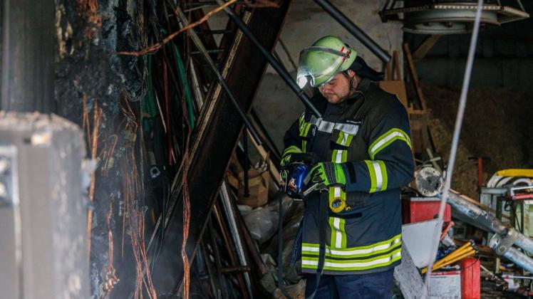 Ein Feuerwehrmann vor der zerstörten Elektroversorgung in einer Scheune in Lintorf.