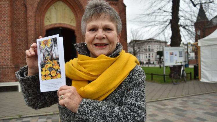 Organisatorin Dora Riss zeigt das Motiv von Malerin Heidi Hopfmann aus Hohe Düne für die neuen Postkarte, die in diesem Jahr zugunsten der Warnemünder Kantorei verkauft wird.