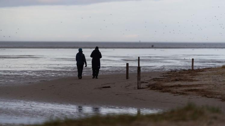 Spaziergänger gehen am Nordseestrand spazieren.
