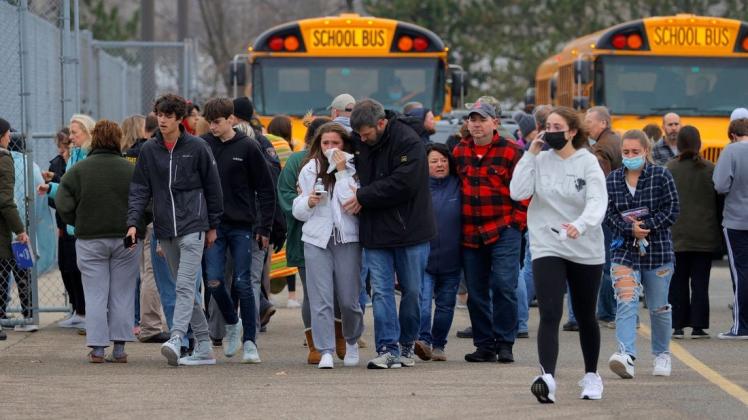 Eltern verlassen mit ihren Kindern einen Parkplatz, wo sich viele Schüler nach einer Schießerei an der Oxford High School im US-Bundesstaat Michigan versammelt haben.