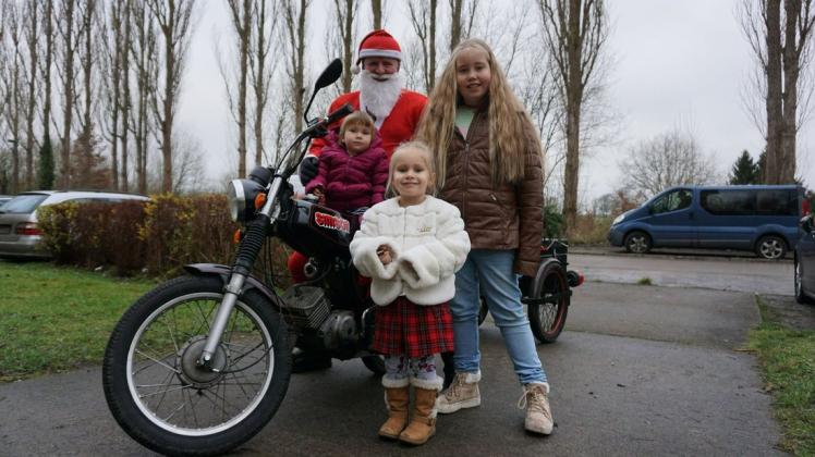 Der Weihnachtsmann, alias Roland Schmidt, fährt auf dem Moped durch Hagenow, um Weihnachtsfreude zu versprühen. Das finden auch Bente, Pia und Hanna (v.l.) super.