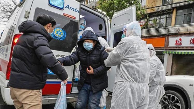 Krankenhausmitarbeiter in Wuhan helfen einem Patienten aus einem Krankenwagen. 