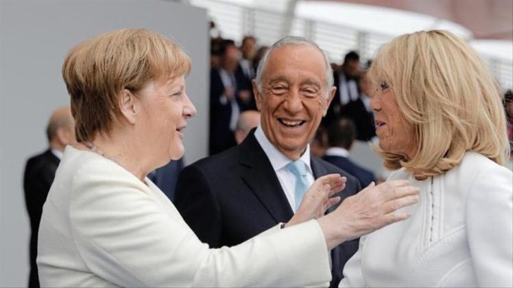 Bundeskanzlerin Angela Merkel (l) und Brigitte Macron begrüßen sich. Viele europäische Staats- und Regierungschefs verfolgen auf der Ehrentribüne die Militärparade. 