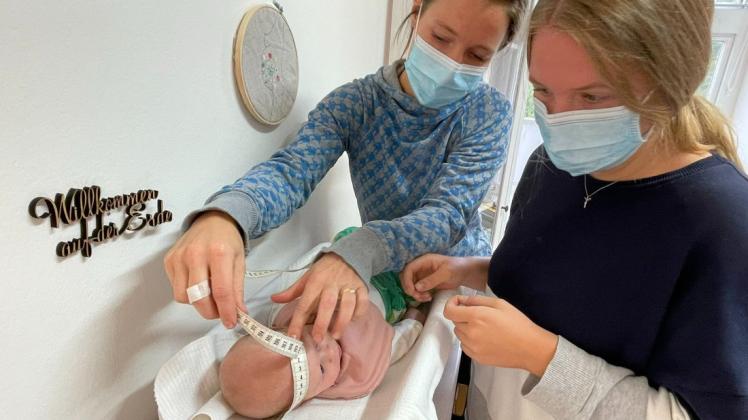 Hebamme Marie Göttsch (links) misst mit Studentin Laura Baaß den Kopfumfang eines elf Wochen alten Babys.