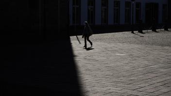 Eine Fußgängerin überquert am Dienstag bei Sonnenschein den Domplatz in Osnabrück. Ab Mittwoch gelten für die Menschen in Stadt und Landkreis Osnabrück Ausgangsbeschränkungen wegen der Corona-Pandemie.