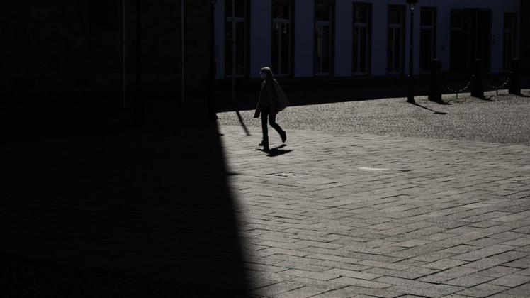 Eine Fußgängerin überquert am Dienstag bei Sonnenschein den Domplatz in Osnabrück. Ab Mittwoch gelten für die Menschen in Stadt und Landkreis Osnabrück Ausgangsbeschränkungen wegen der Corona-Pandemie.