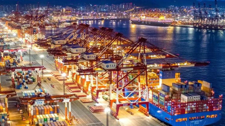 Containerschiffe liegen im nächtlich beleuchteten Containerterminal des Hafens von Qingdao. Containerschiffe liegen im nächtlich beleuchteten Containerterminal des Hafens von Qingdao.