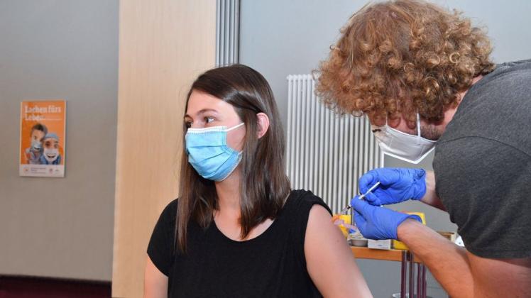 Impfarzt Simon Krauß (r.) vom städtischen Impfzentrum verabreicht Caroline Flägel von der Kardiologie an einer der Impfstationen im Hörsaal ihre dritte Impfung gegen Corona.
