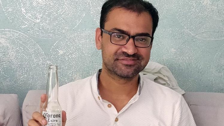 Kovid Kapoor hält eine Flasche Corona-Bier in der Han.