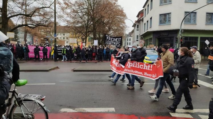 Impf-Gegner laufen an der Gegen-Demo am Willy-Brandt-Platz in Osnabrück vorbei. Pfeifkonzert auf beiden Seiten.